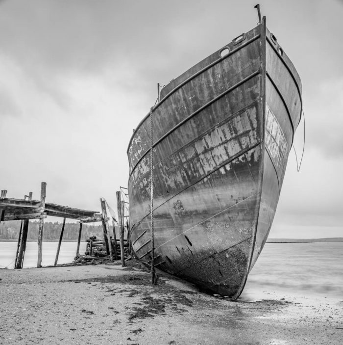A rusting ship settles into the mud at low tide