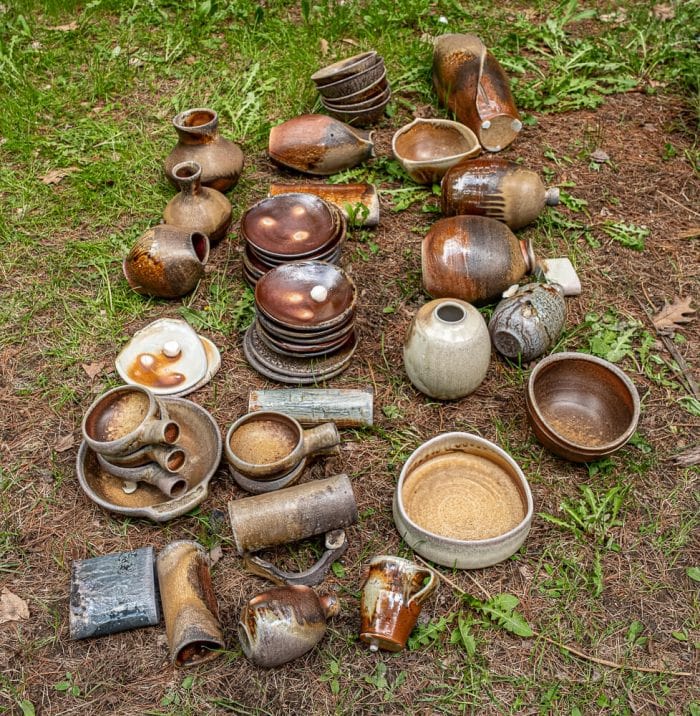 A variety of plates andpots and bowls lie on the ground .