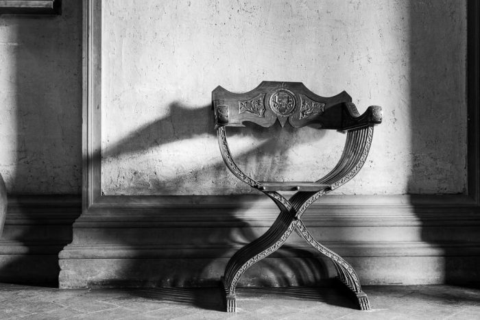 A fancy chair against a wall at teh entrance to a Florence Museum