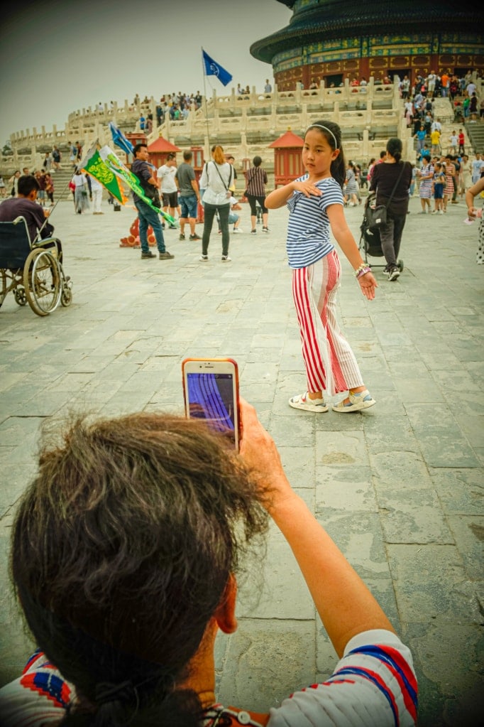 A mother photographs her daughter posing in front of the Hall of Prayer.