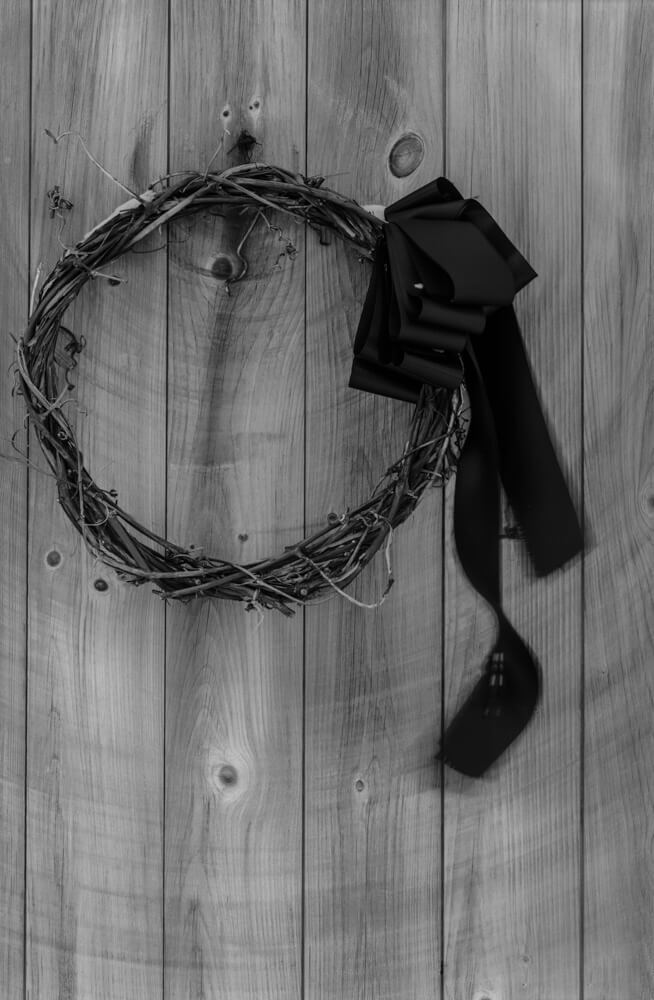 An old wreath with black ribbon hangs on the front door of the Olson House