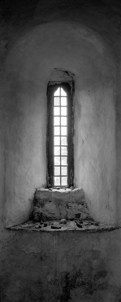 A tiny window in with two layers of stones left by visitors to Iona.